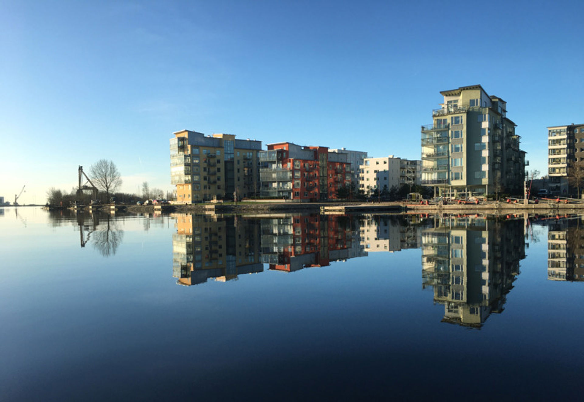 Flerfamiljsfastigheter utmed vattnet. Fastigheterna speglas i vattnet som är Nissan i Halmstad.